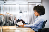 Woman with glasses working on a laptop behind a desk